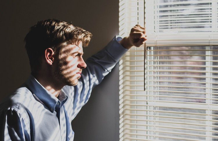 Frühjahrsmüdigkeit & Frühjahrsdepression: Symptome, Unterschiede & Auswege Artikel Frühjahrsmüdigkeit Mann vor einem Fenster