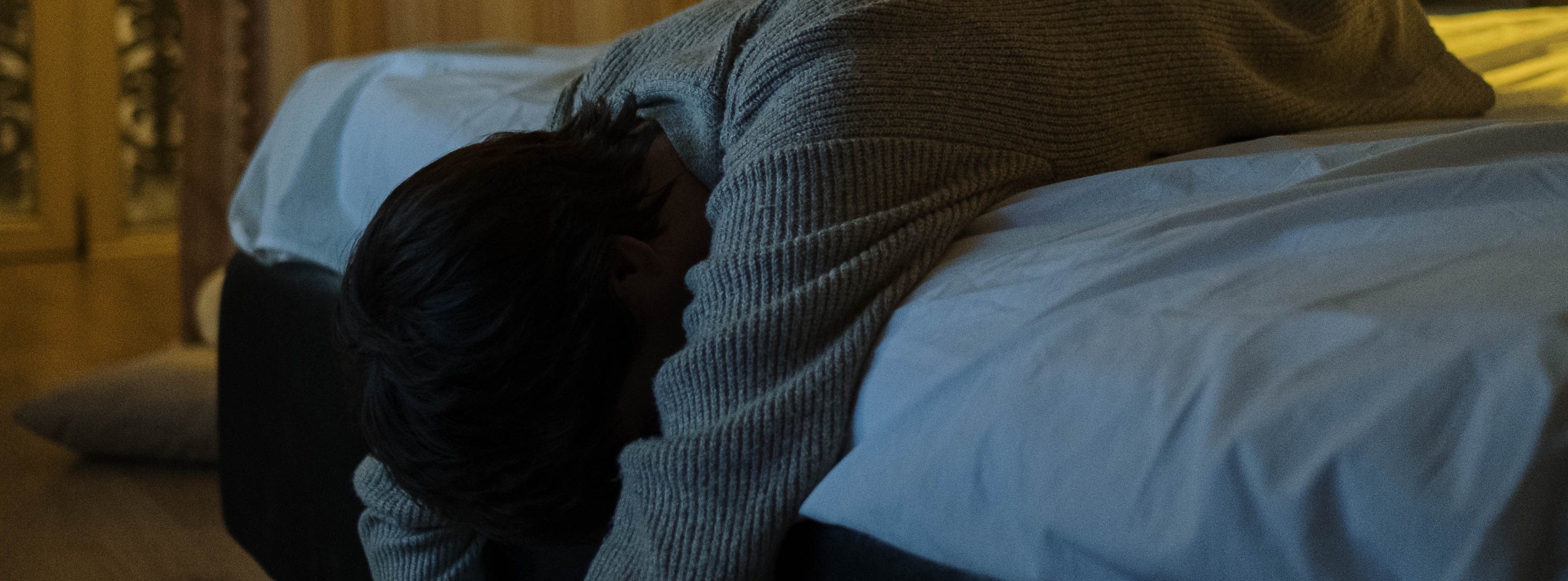 Frau liegt erschöpft auf einem Bett in einem Raum