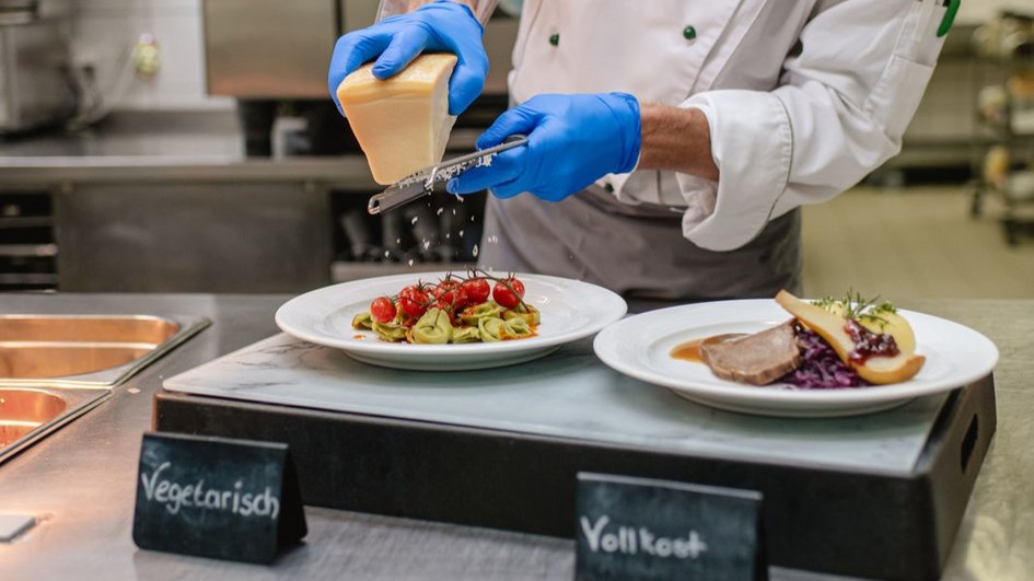 Chefkoch reibt Käse über ein Gericht