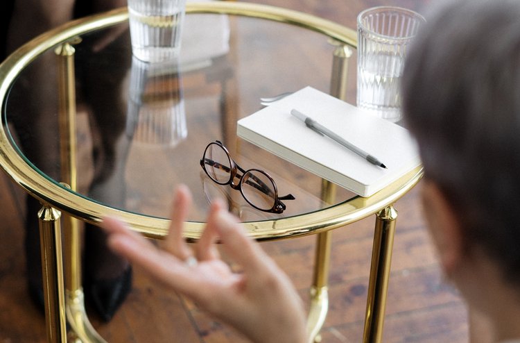 Psychotherapie bei Oberberg Zwei Personen sitzen sich gegenüber mit einem Tisch in der Mitte