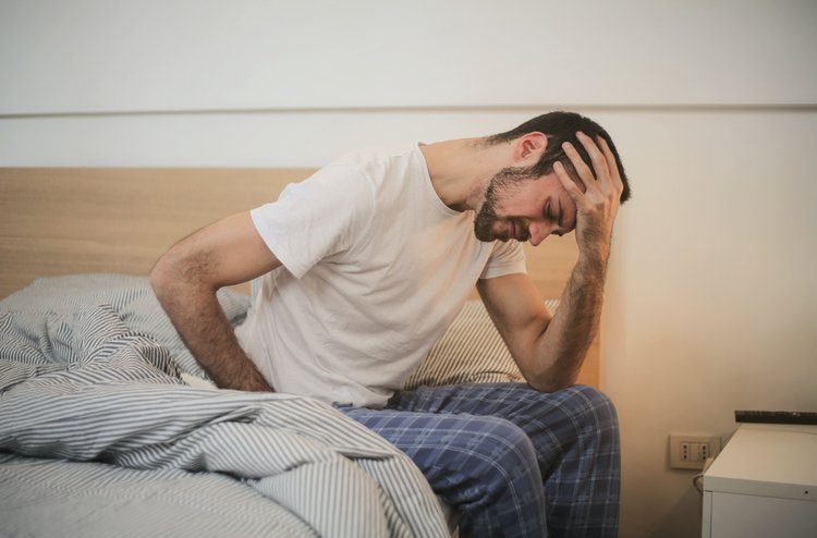 physische Schmerzen Mann sitzt mit schmerzendem Rücken auf dem Bett