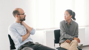 Klinikaufnahme Ein Mann und eine Frau sitzen auf Stühlen und sprechen miteinander.