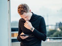 Internetsucht - Mann in schwarzem Oberteil, der auf sein Handy starrt