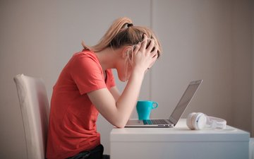 Frau sitzt vor Laptop schlägt die Hände zusammen
