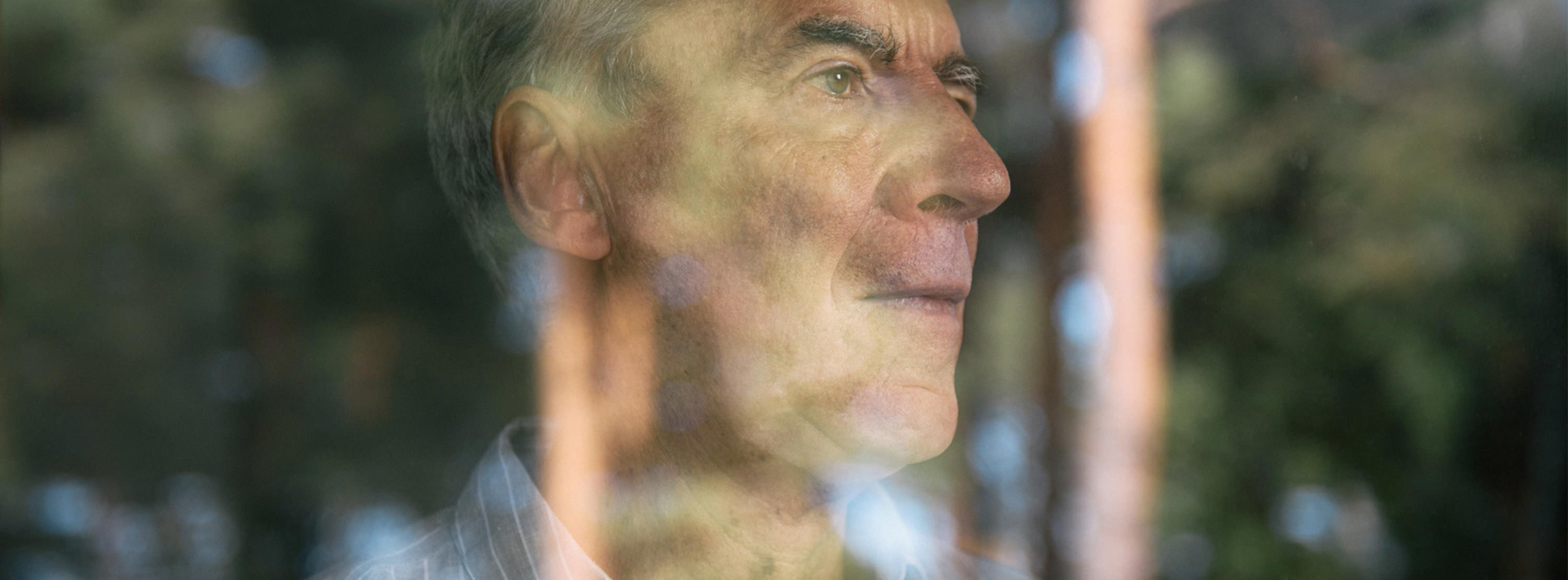 Mann hinter spiegelnder Fensterscheibe in Behandlungsraum