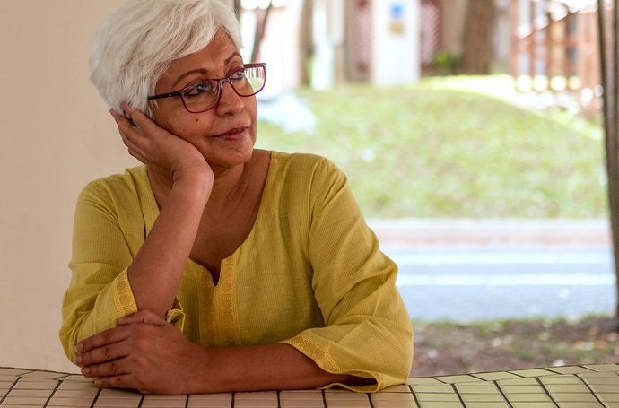 Vogelzwitschern und Sonnenstrahlen – trotzdem frühlingsmüde? Artikel Frühlingsmüdigkeit alte Frau am Tisch