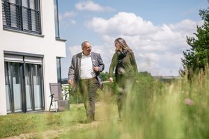 Dr. med. Ahmad Bransi im Gespräch mit einer Patientin Chefarzt Dr. med. Ahmad Bransi und eine Patientin bei einem Therapiegespräch, im Hintergrund die Klinik und grüne Umgebung