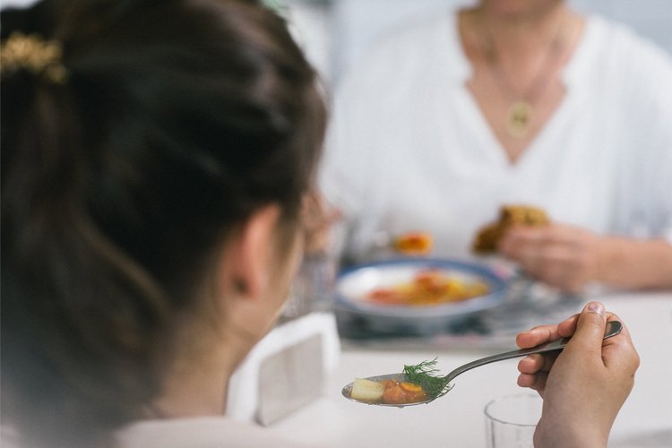 Frau mit Löffel voller Suppe am Esstisch