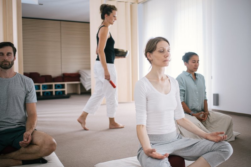 Yogaübung mit Patienten und einer THerapeutin im Hintergrund