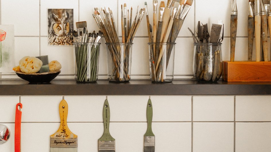 Regalbrett auf denen Gläser voll mit Pinseln stehen