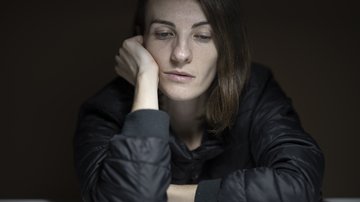 Die Folgen von Covid-19 für die Psyche – Depressionen in der Pandemie Frau in grauem Oberteil guckt traurig