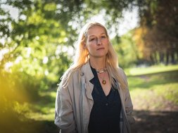 frau spaziert durch Park, besorgter Blick