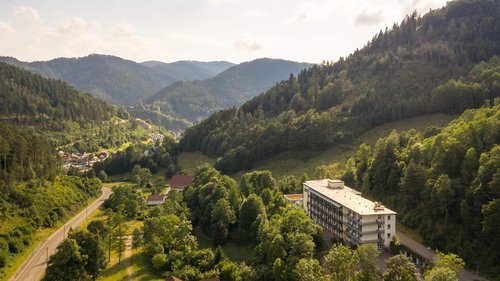 Oberberg Fachklinik Schwarzwald Kastenartiges Gebäude aus der Vogelperspektive in Mitten von bewaldeten Bergen.
