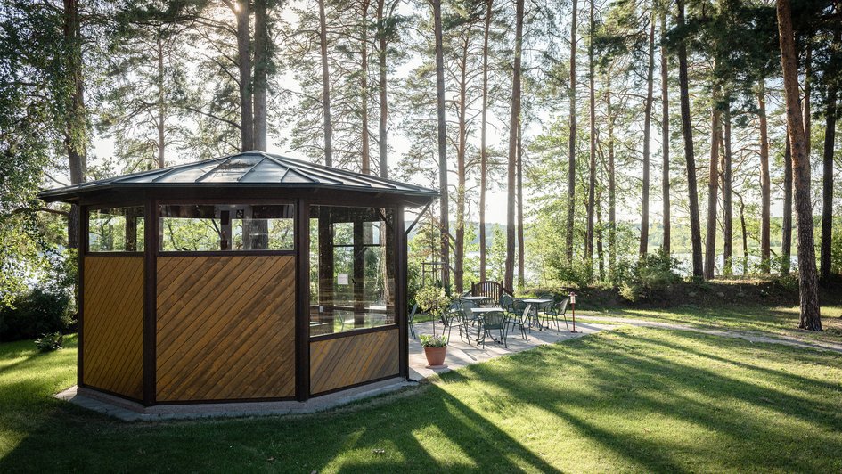 Freizeit und Umgebung  Ein Holzpavillon  auf einer Wiese. Im Hintergrund Bäume.
