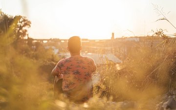 Morgenroutine & Meditation: Bewusst in den Tag starten - Tipps Artikel Meditation: Ein Mann sitzt im Feld