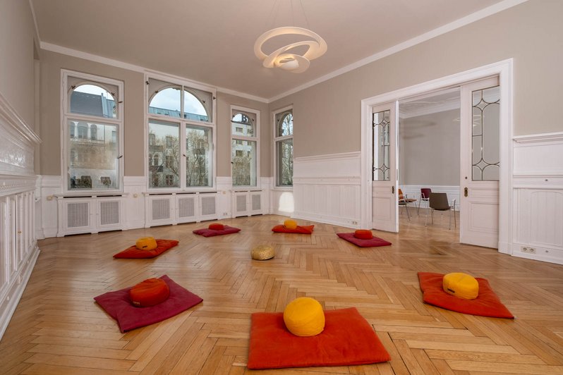 großer Raum mit roten Matten und Sitzkissen auf dem Boden