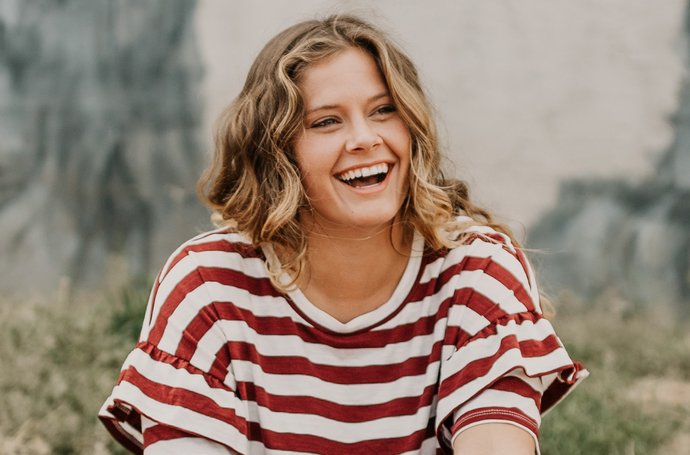 Depression - Eine junge lächelnde Frau in einem rot-weißen Oberteil