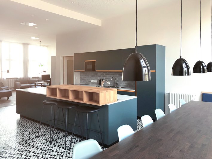 moderne Patientenküche mit langem dunkklem Esstisch im Vordergrund