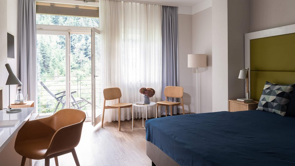 Patientenzimmer Patientenzimmer mit großem Bett, Sitzgelegenheiten und offener Tür zum Balkon