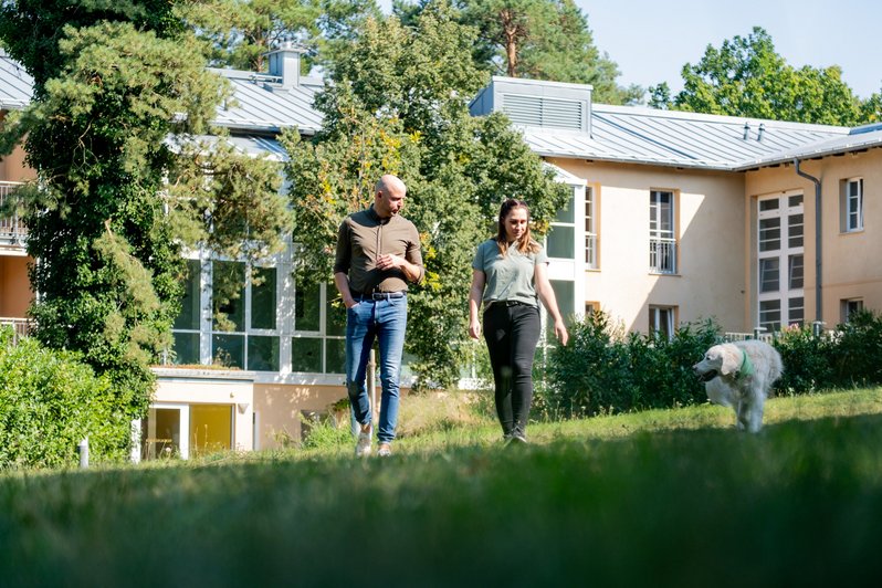 Interaktion zwischen Therapeut Therapiehund und Patient im Garten der Fachklinik Potsdam