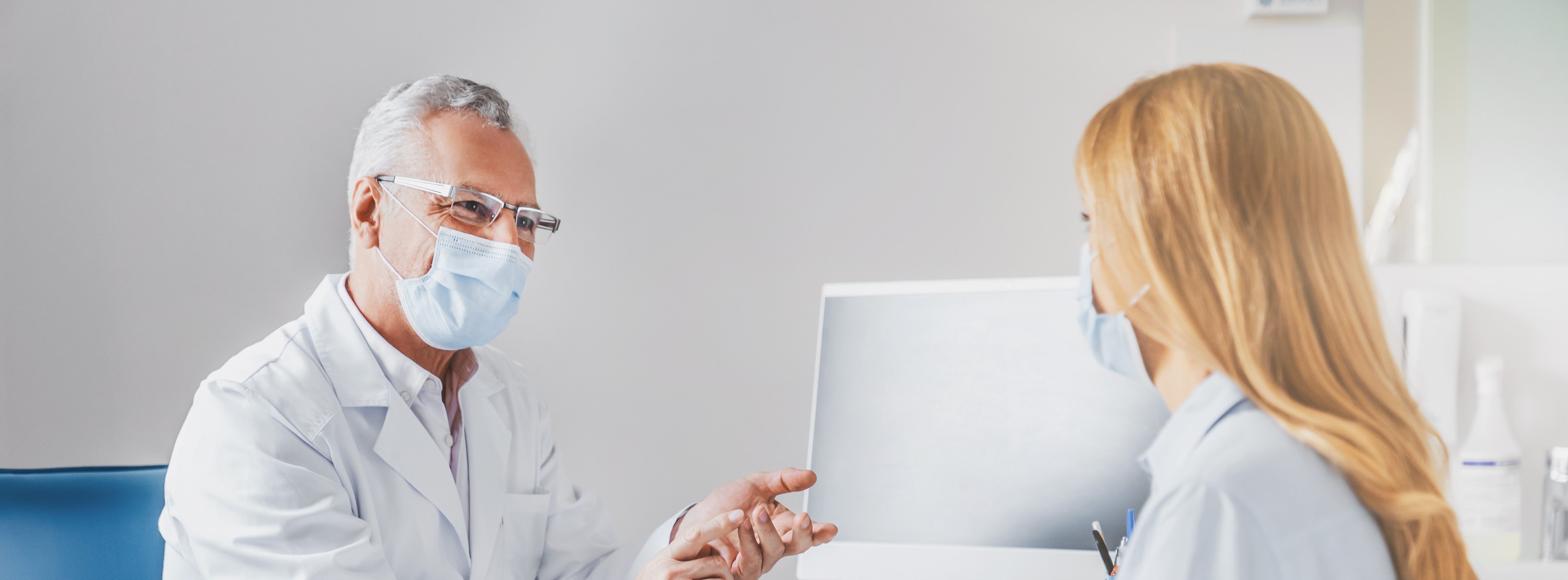 Patientin und Arzt im weißen Kittel sitzen sich im Besprechungszimmer gegenüber