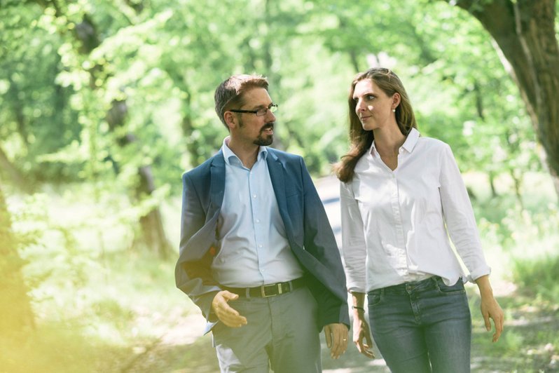 In der Natur findet ein Therapiegespräch zur Behandlung Somatoformer Störungen statt, Bäume und grüne Blätter im Hintergrund