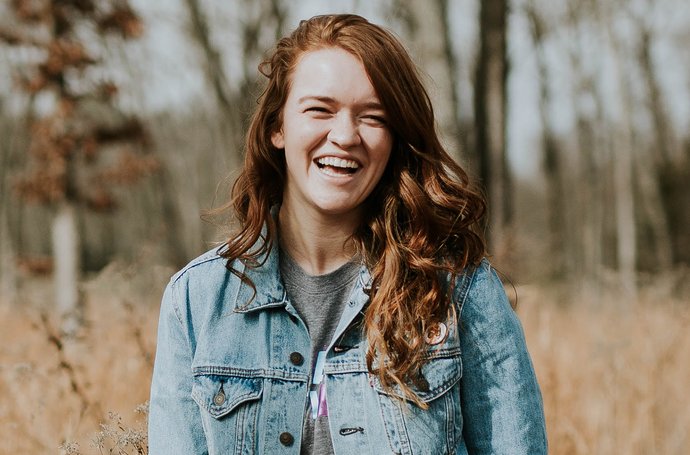 Ernährung - Ein Mädchen im Wald mit rot-braunen Haaren lacht in die Kamera
